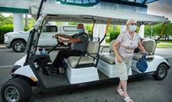 礼貌购物车 at 主入口 with masked patient stepping off cart