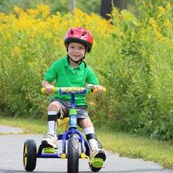 Child wearing a helmet while riding a tricycle